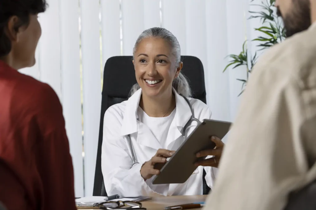 Médica sorridente em consulta com dois pacientes que marcaram horário pela plataforma de agendamento virtual da Burnup.