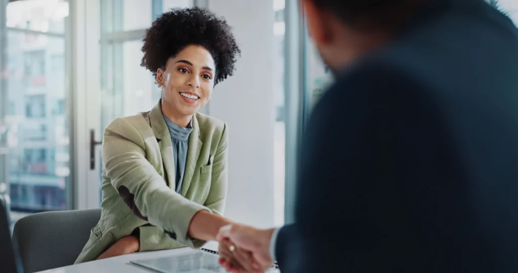 Foto de profissional de RH (Recursos Humanos) sorrindo, apertando a mão do CEO com planos de implementar o salário emocional na empresa.
