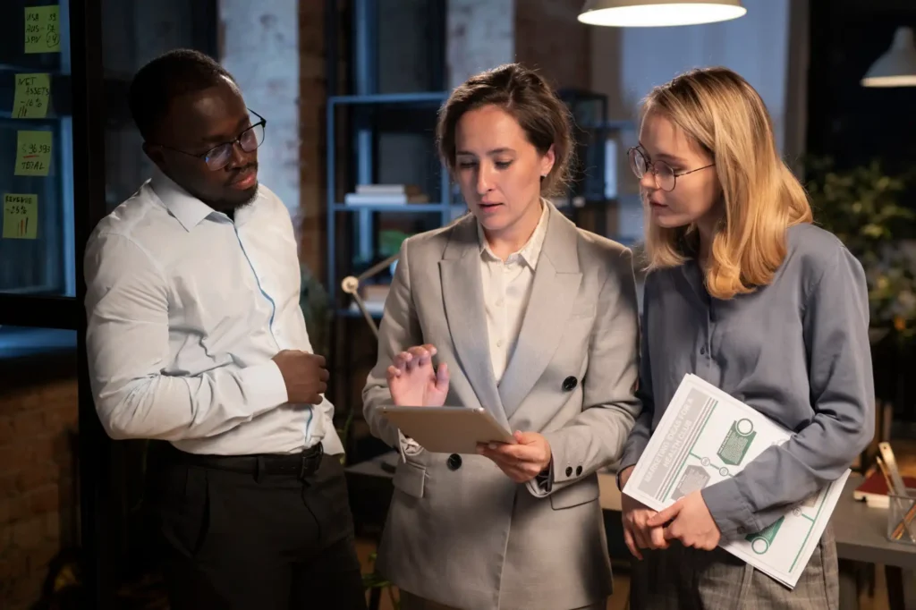Foto de três colaboradores dos setores de Recursos Humanos e Financeiro analisando relatórios com os índices do absenteísmo e presenteísmo, mostrando os impactos negativos dos fenômenos nas finanças de sua organização.