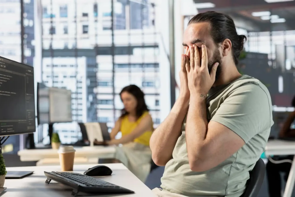 Foto de um colaborador mentalmente exausto durante seu expediente de trabalho, demonstrando como o absenteísmo e presenteísmo atingem os colaboradores e prejudicam as organizações.