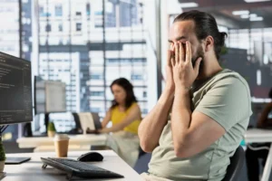 Foto de um colaborador mentalmente exausto durante seu expediente de trabalho, demonstrando como o absenteísmo e presenteísmo atingem os colaboradores e prejudicam as organizações.