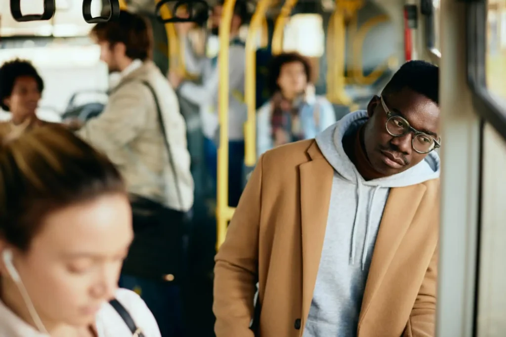 Foto de um homem expressando cansaço no transporte público no caminho para o seu trabalho, ilustrando como causas externas podem contribuir para o absenteísmo e presenteísmo nas empresas.