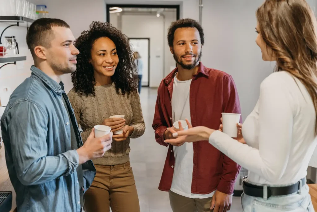 Foto de colaboradores conversando em espaço de convivência no trabalho, reforçando a importância da comunicação aberta e do combate à cultura do estigma.