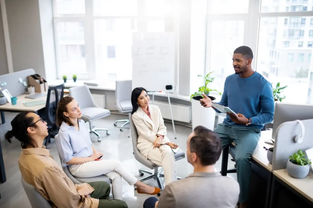 Foto de uma equipe diversa em reunião colaborativa em escritório moderno, discutindo estratégias para promover equilíbrio vida-trabalho na empresa.