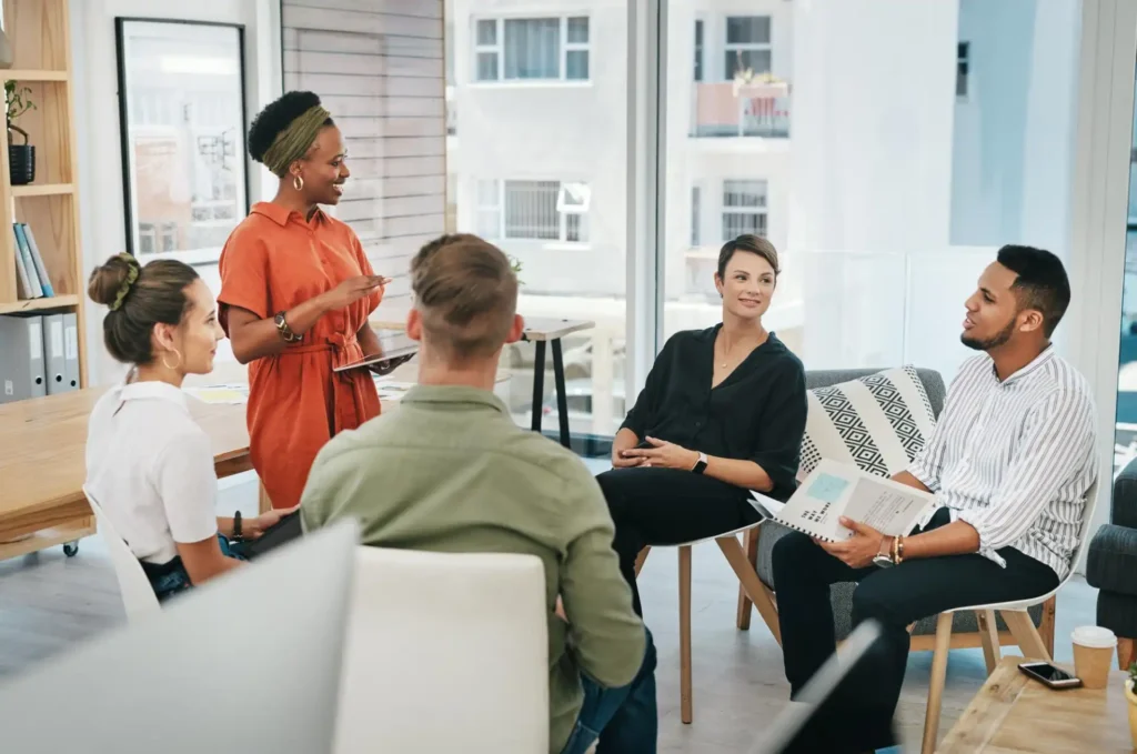 Foto de uma equipe diversa em uma reunião corporativa com liderança e equipe engajada, representando o employer branding na retenção de talentos e fortalecimento da cultura organizacional. 